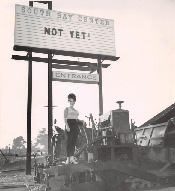 Sue Larson poses atop a paving machine being used to prepare an extension of Kingsdale Avenue west of South Bay Center to allow for entrance to the center from its western end. Dec. 11, 1962 Daily Breeze file photo.