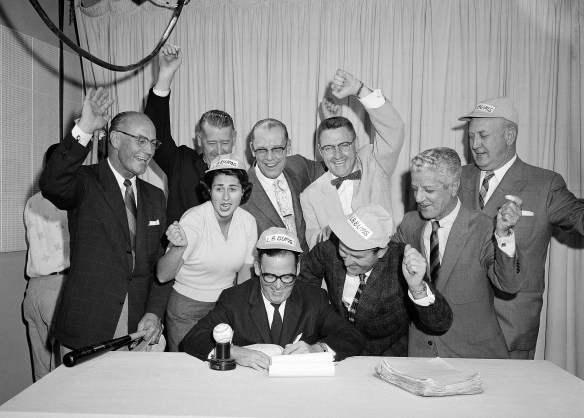 A happy band of Los Angeles City Councilmen and Councilwoman, watch as Mayor Norris Poulson, center, signs the ordinance they passed the previous day, which legalizes a contract between the city and the Brooklyn Dodgers to play at L.A. the following year, Oct. 8, 1957, Los Angeles, Calif. From left to right are: Ransom Callicott, John Gibson Jr., Rosalind Wyman, L.E. Timberlake, James Corman, Gordon Hahn, Charles Navarro and Everett Burkalter. (AP Photo/Don Brinn)