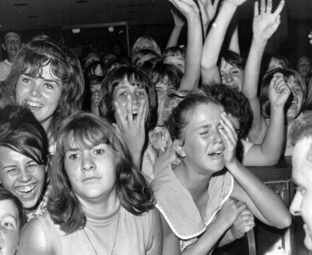 Just the sight of The Beatles from a distance caused this reaction among a group of Girls at the Los Angeles International airport in this Aug.18, 1964 file photo. Airport security kept the British singers away from several thousand youngsters during a brief stopover in Los Angeles en route to San Francisco. (AP Photo/stf)