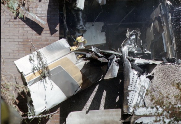 A firefighter attempts to untangle part of the wing of the Cessna that crashed into a Torrance medical building on Sept. 21, 1997, killing all 4 aboard. (Daily Breeze staff file photo)