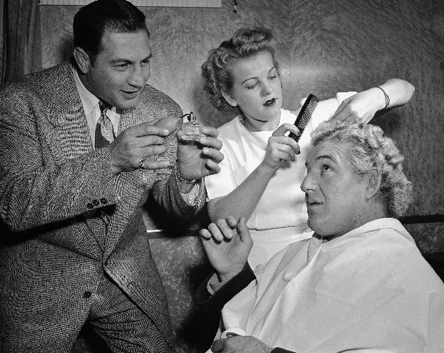 Gorgeous George gets his hair waves before bout in Washington on Nov. 18, 1948. Left to right are Sam Menacker, business manager; Martha Kunick, beautician and George. (AP Photo)