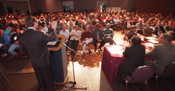 Michael Ovitz, left foreground, talks about football stadium proposal to several thousand attendees of Town Hall meeting at Carson Community Center on Feb. 6, 1999. (Daily Breeze staff file photo)