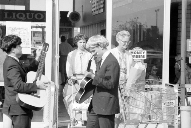 Daily Breeze reporters Jay Berman, left, and Chuck Cole, center, perform their Beatles act outside the Ralphs market at South Bay Center to the bemusement of shoppers. Daily Breeze photo by Bob Jones, Feb. 14, 1964.