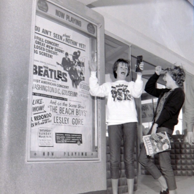 Torrance residents Linda West, 13, clad in Beatles sweatshirt, and Karen Larsen, 13, clutching Beatles magazine, show their enthusiasm after seeing the Beatles' Washington, D.C. concert film on a closed circuit showing at the Fox Redondo Theatre on March 14, 1964. Daily Breeze file photo.